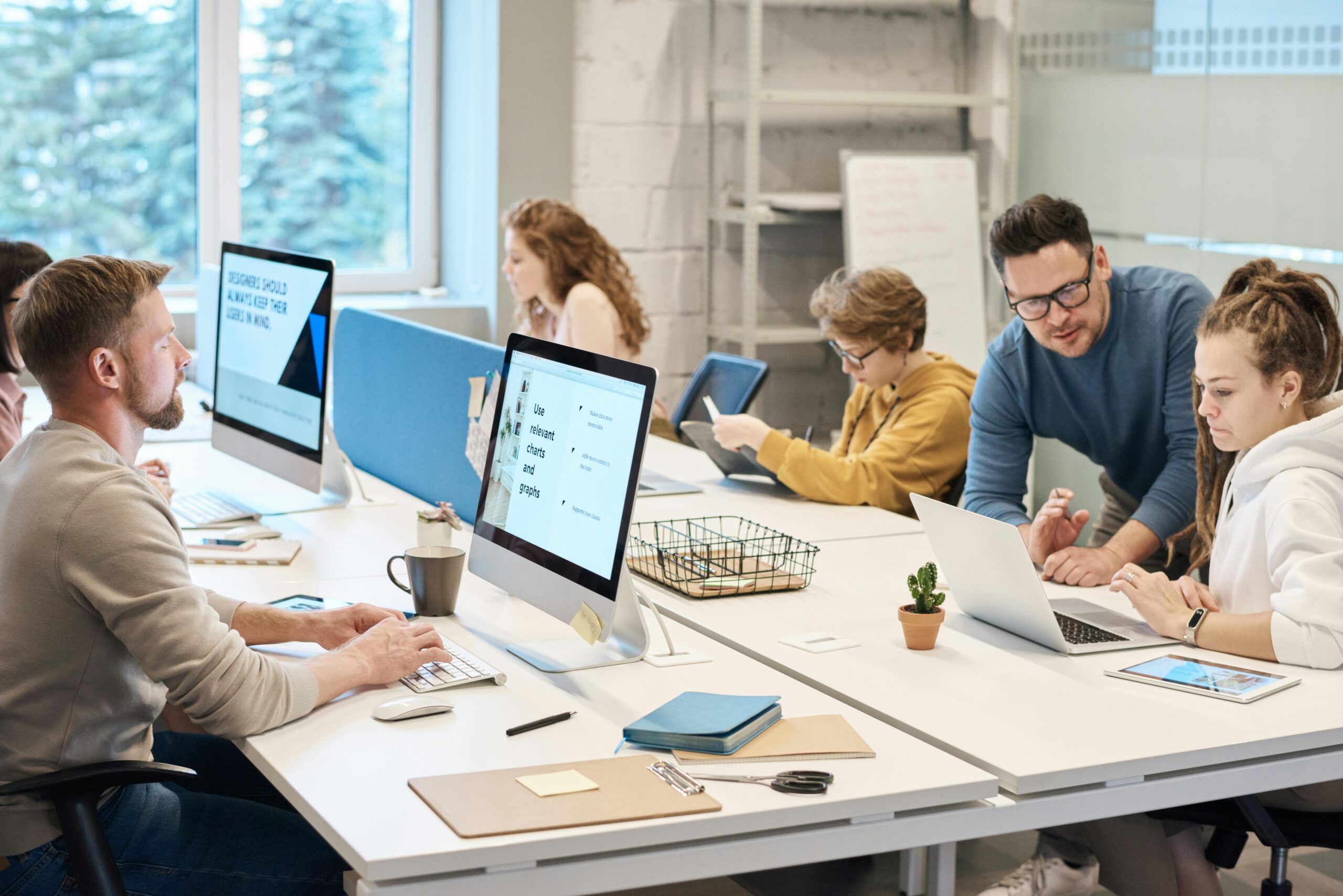 4 people working at different desks and computers discussing Analytics