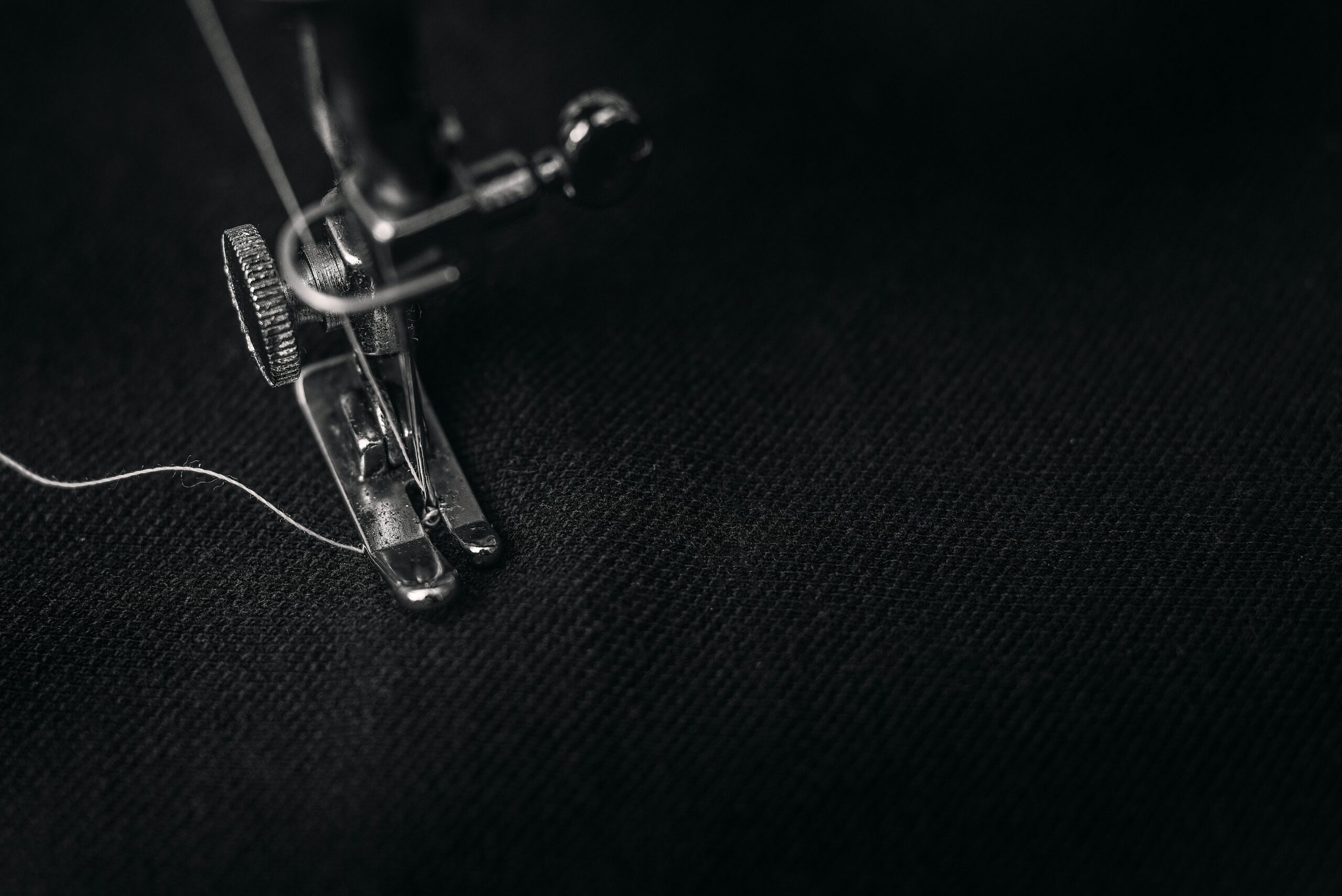 Close up view of sewing machine needle sewing into black fabric
