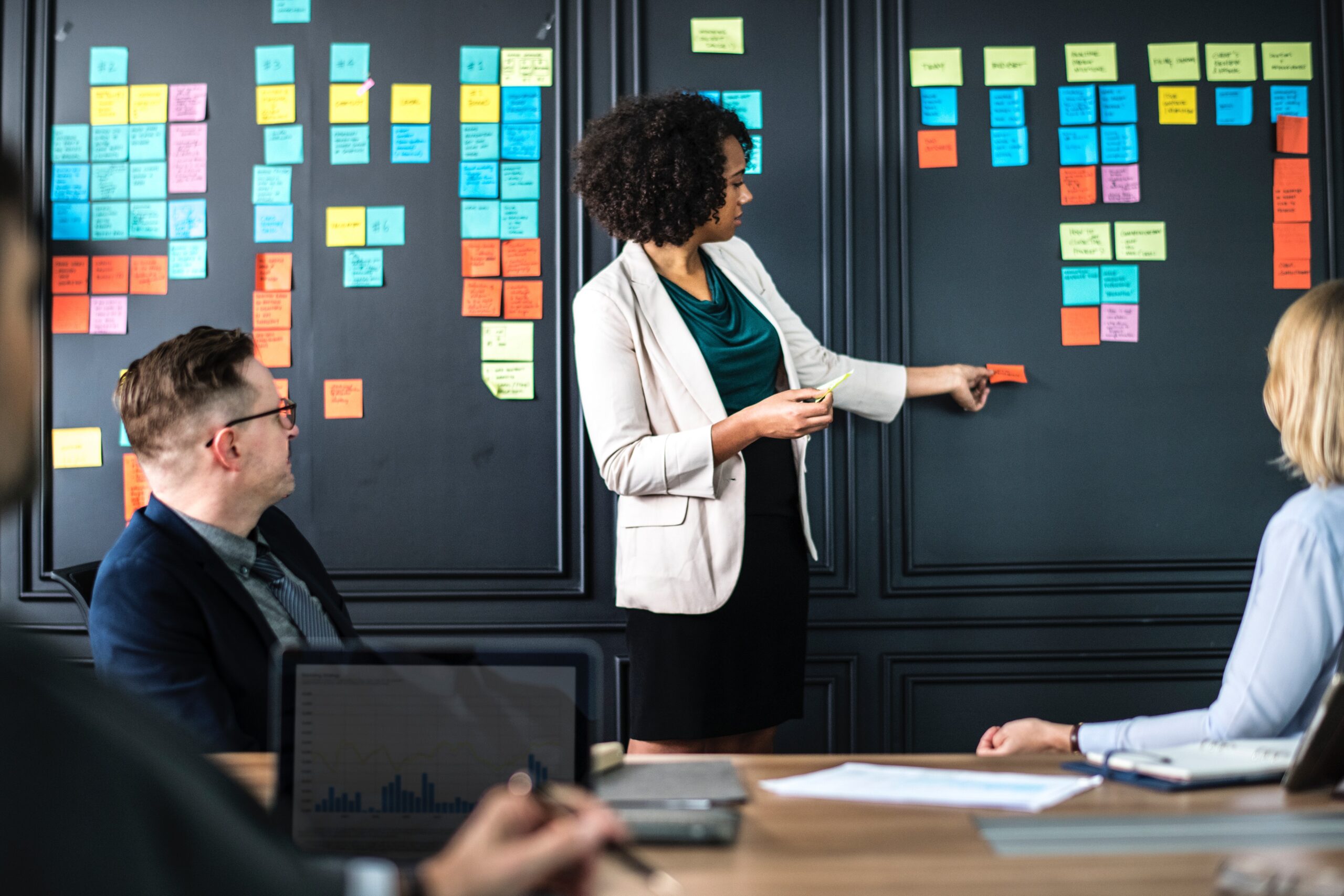 Adult standing in front of a board with sticky notes on it