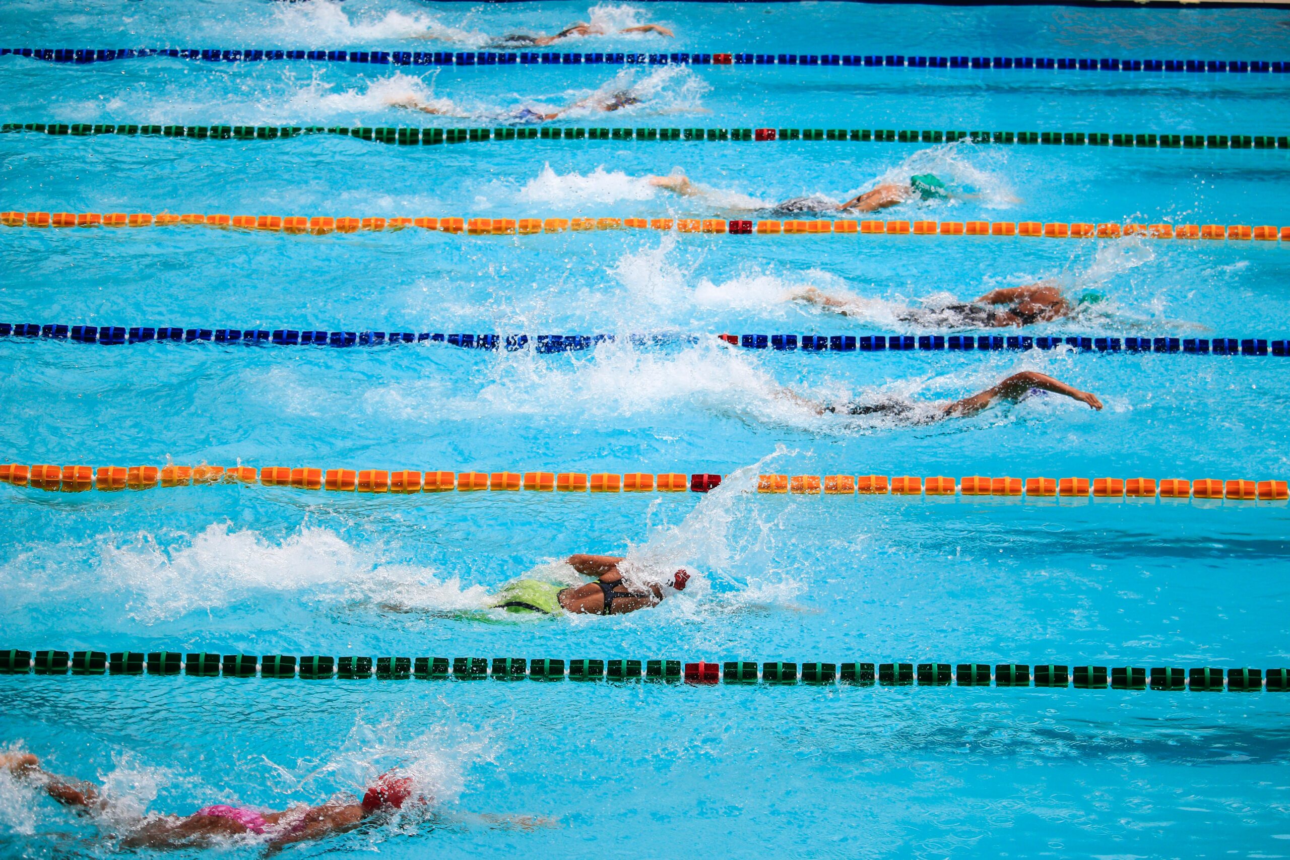 7 swimmers in separate lanes, swimming in a race
