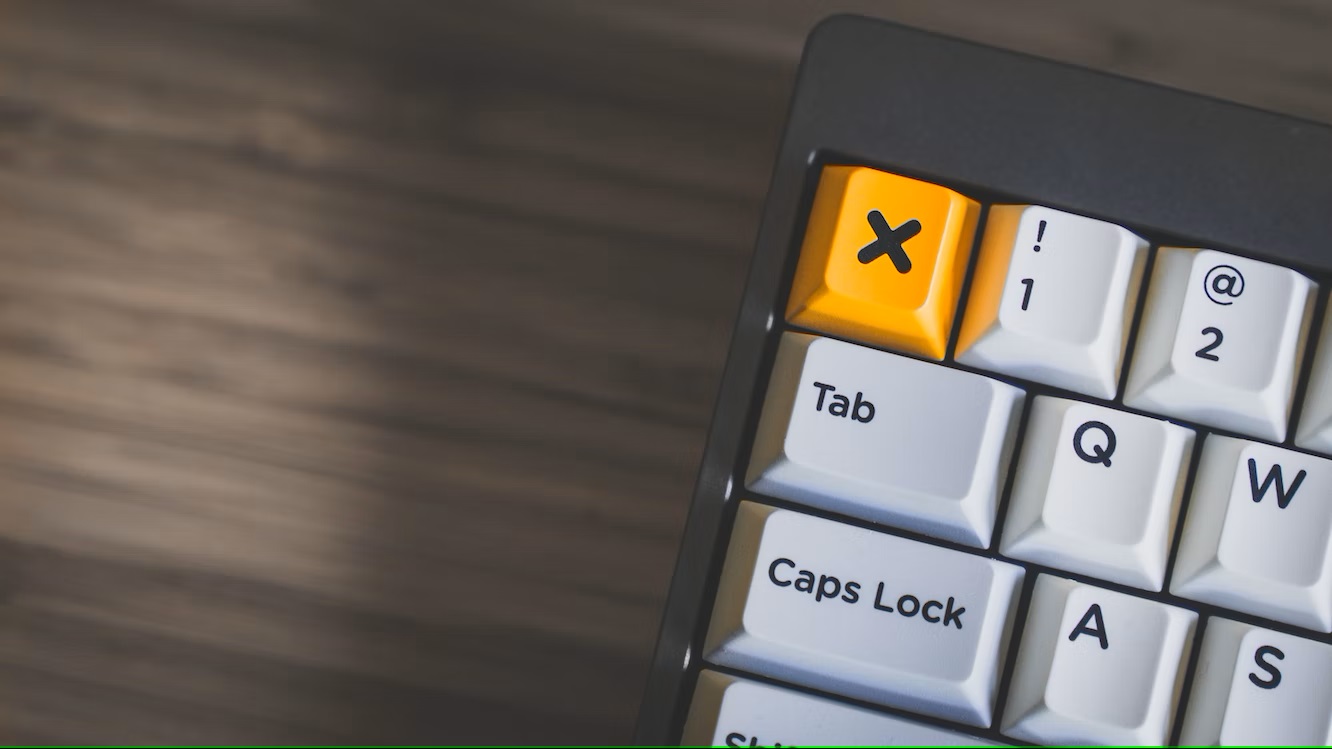 Corner of a laptop with a yellow button and a black cross.