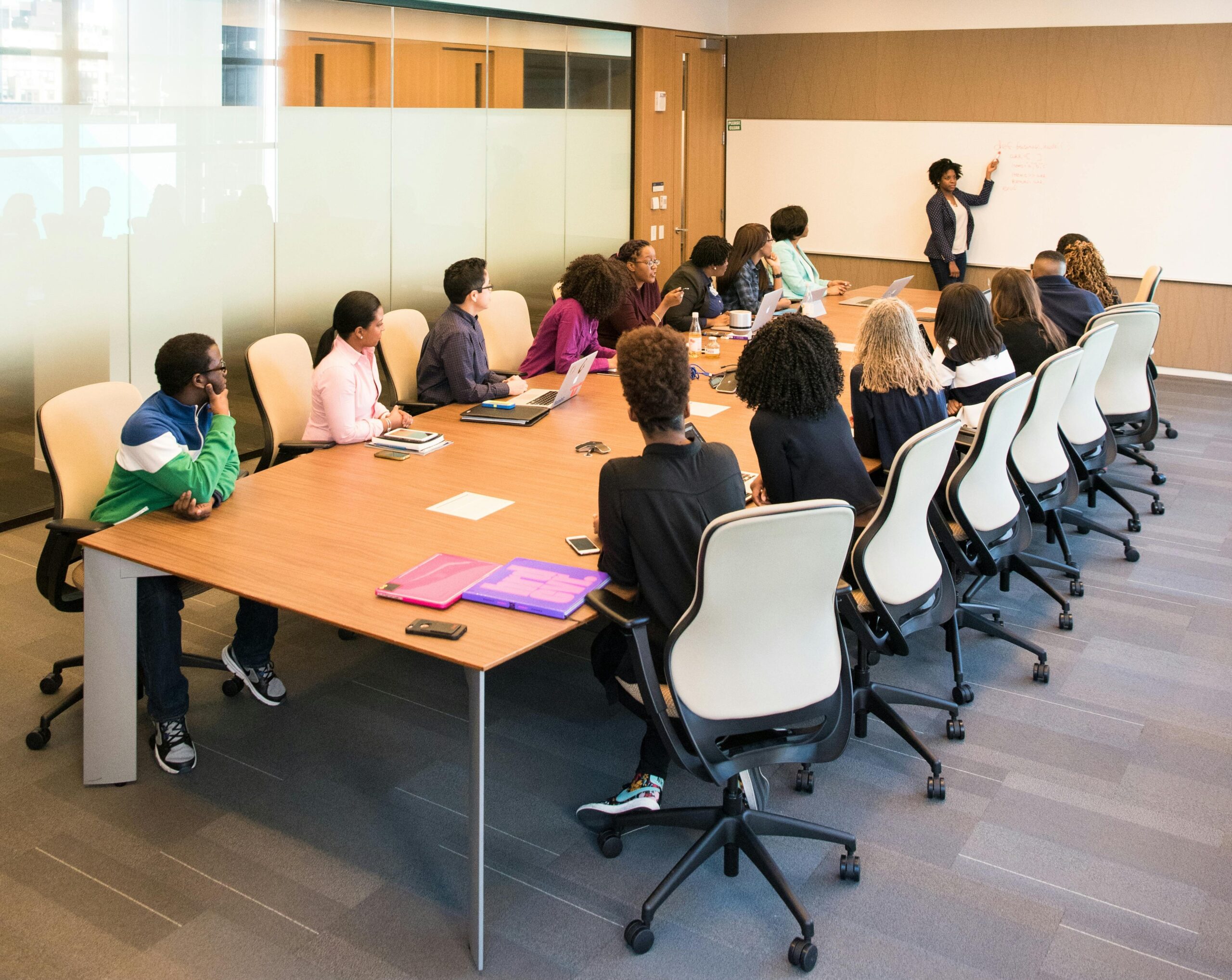 16 people sitting in a boardroom meeting